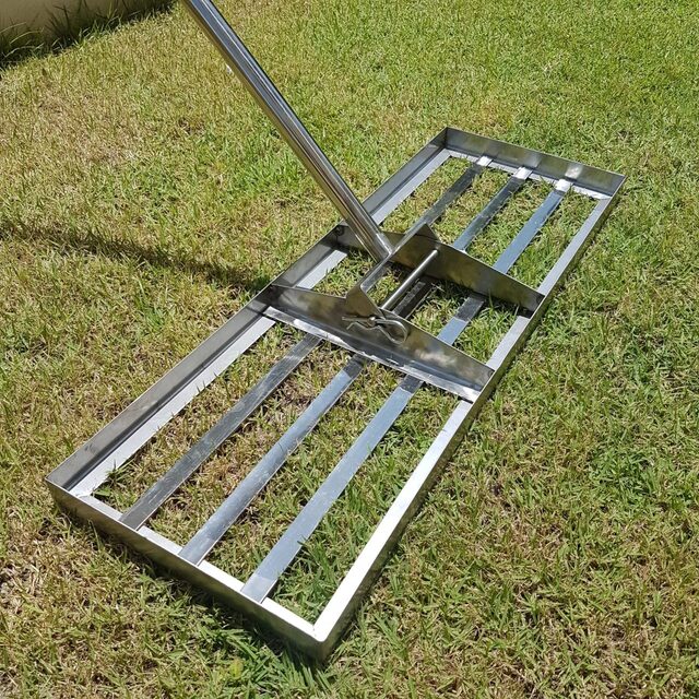 Stainless steel lawn lute head resting on a lawn, with its locking pin and handle